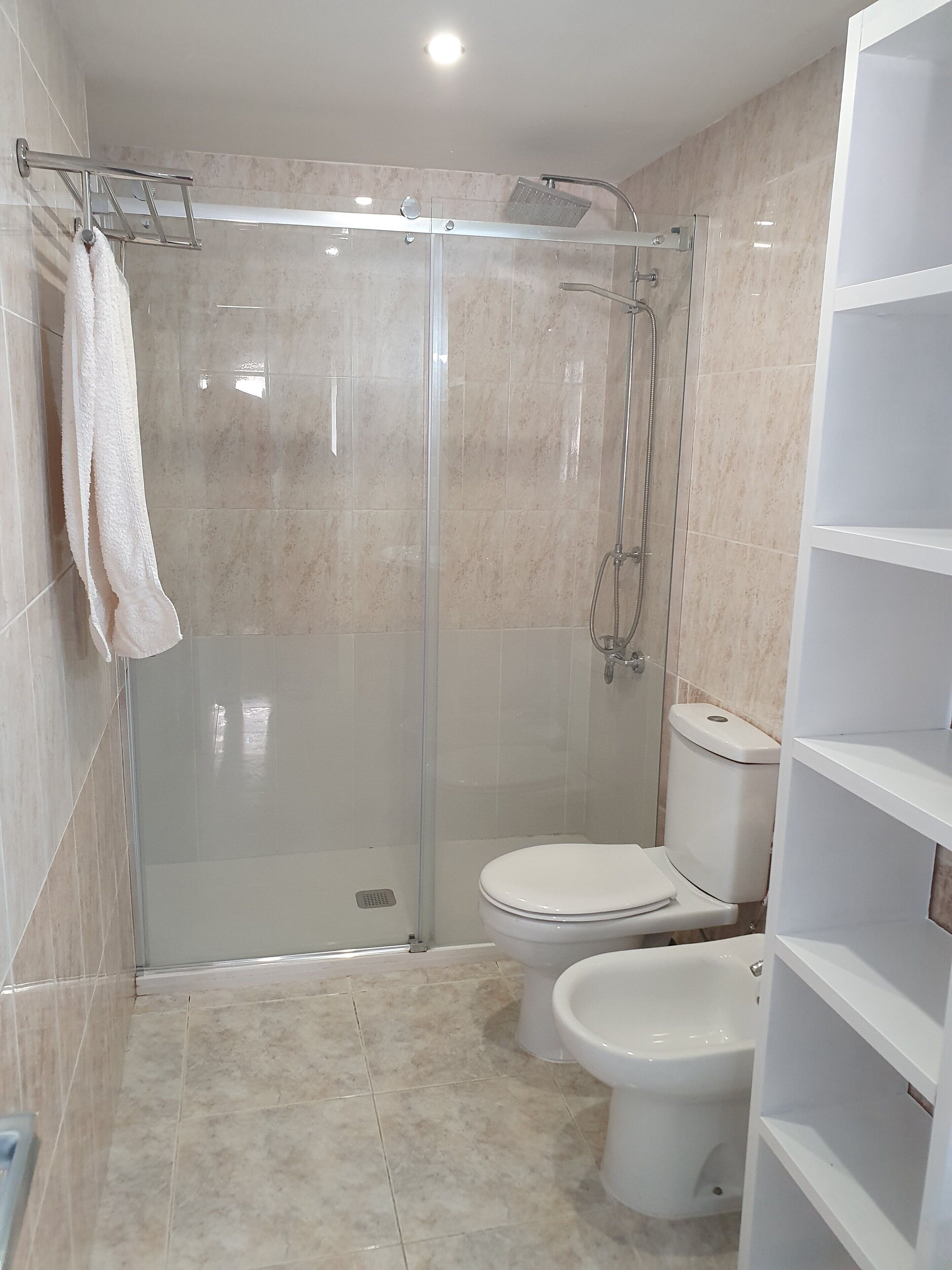A modern bathroom with a glass-enclosed shower, a toilet, and a bidet.