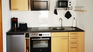 Eine kompakte Küche mit Backofen, Mikrowelle, Kaffeemaschine und Spüle.