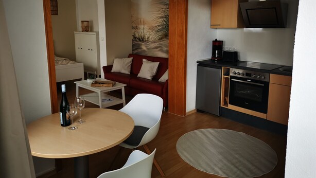 Ein gemütlicher Wohnbereich mit Essplatz, einer Küchenzeile und einem roten Sofa.