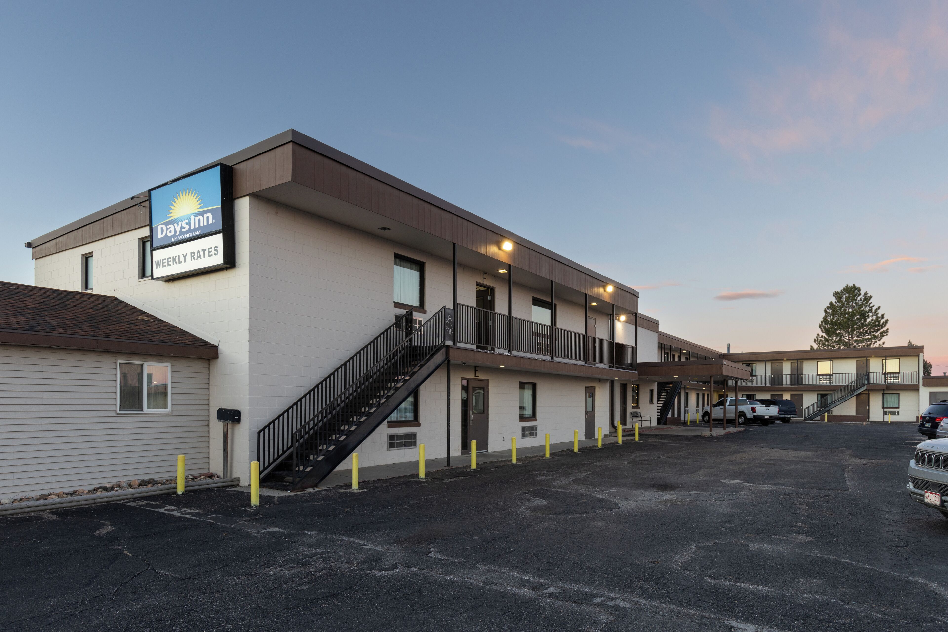 Un motel Days Inn con una estructura de dos pisos, un estacionamiento y una escalera visible que conduce a la entrada.