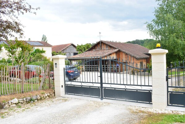 A gated property with a rustic wooden building and a paved driveway.