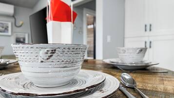 A kitchen with white cabinets, a wooden table, and a white bowl with a red napkin on it.