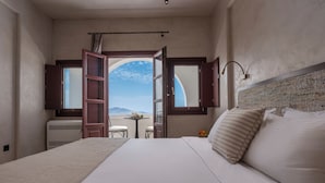 Ein Schlafzimmer mit einem großen Bett, Bergblick durch ein offenes Fenster und einem kleinen Tisch mit Stühlen.