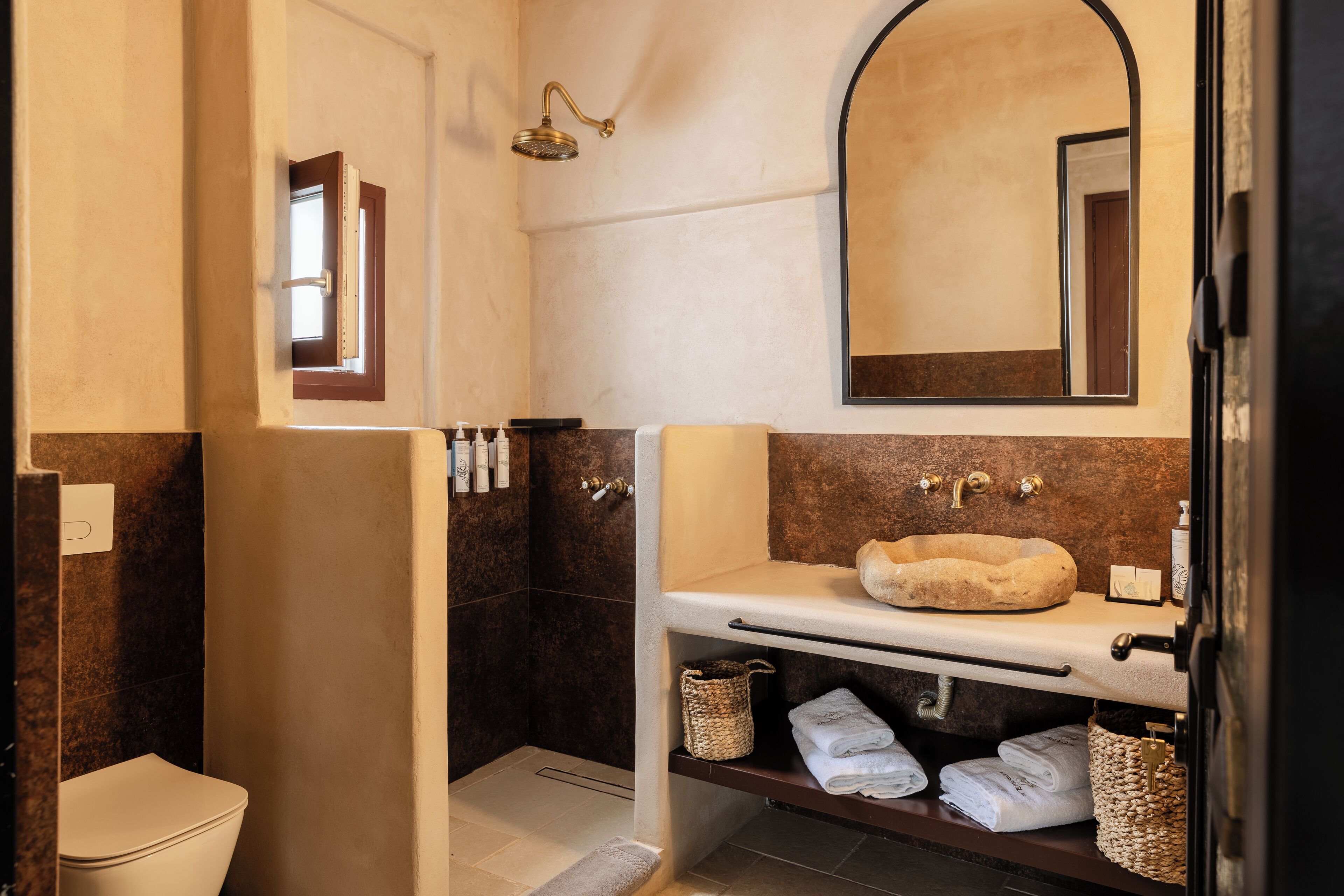 Ein Badezimmer mit einem weißen Waschbecken, einer beige farbenen Badmatte und einer Dusche mit Glastür.
