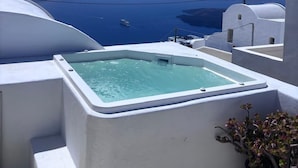 Ein klarer, blauer Himmel, ein weißer Infinity-Pool und Meerblick.