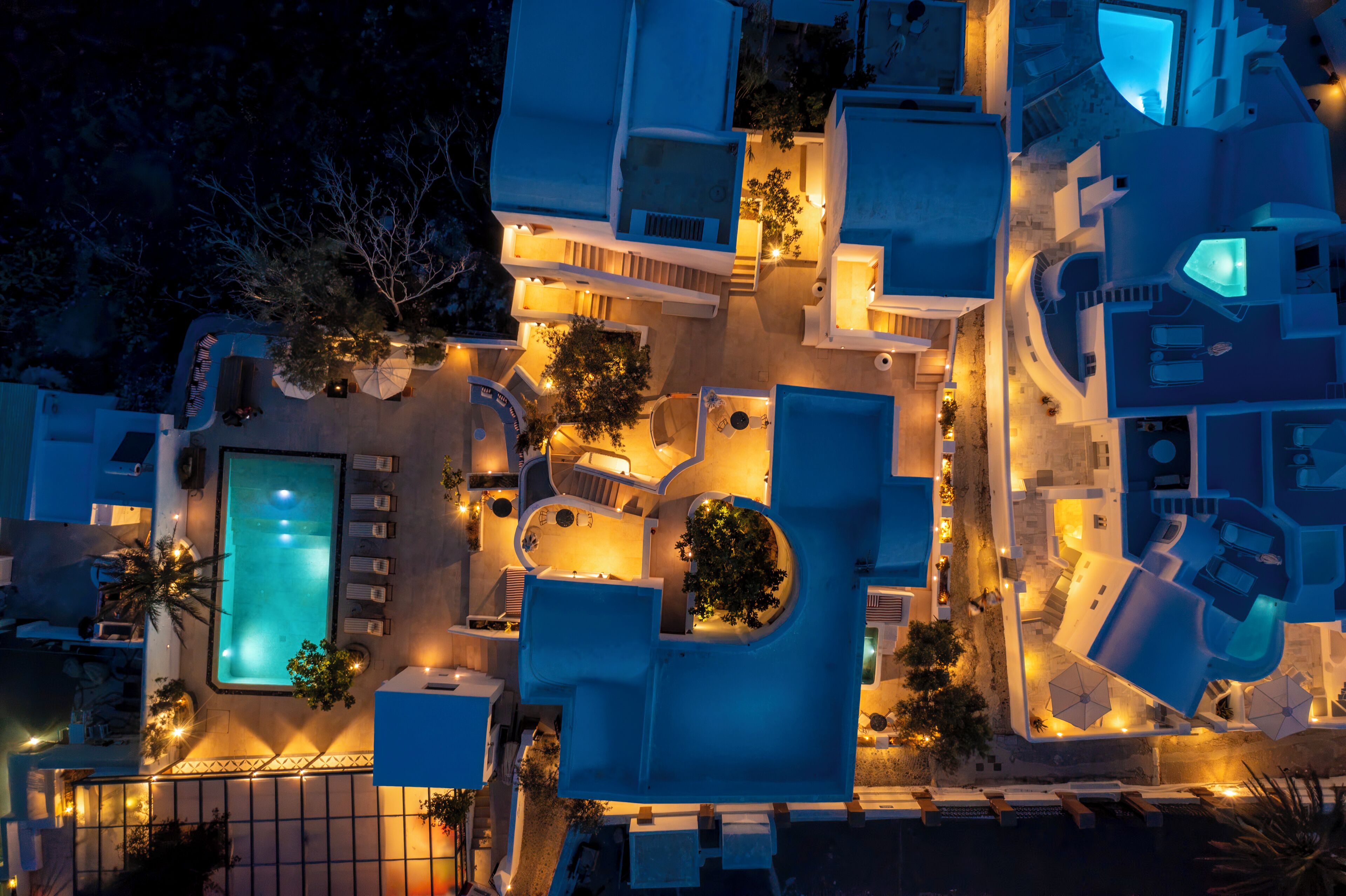 An aerial view of a resort with multiple swimming pools, sun loungers, and a central courtyard.