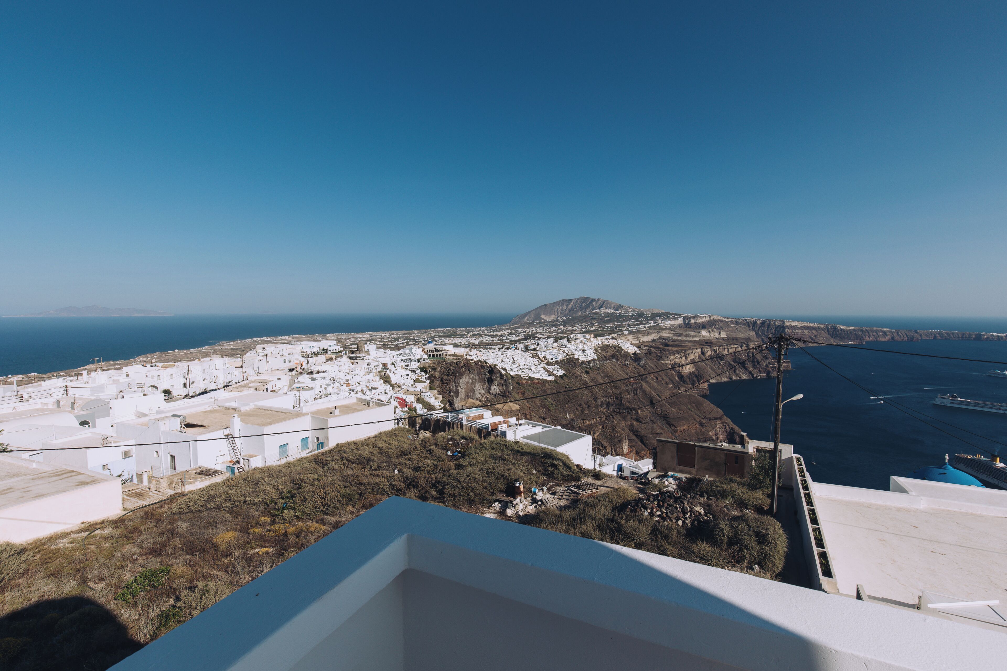 A coastal town with white buildings, a clear sky, and a view of the sea.