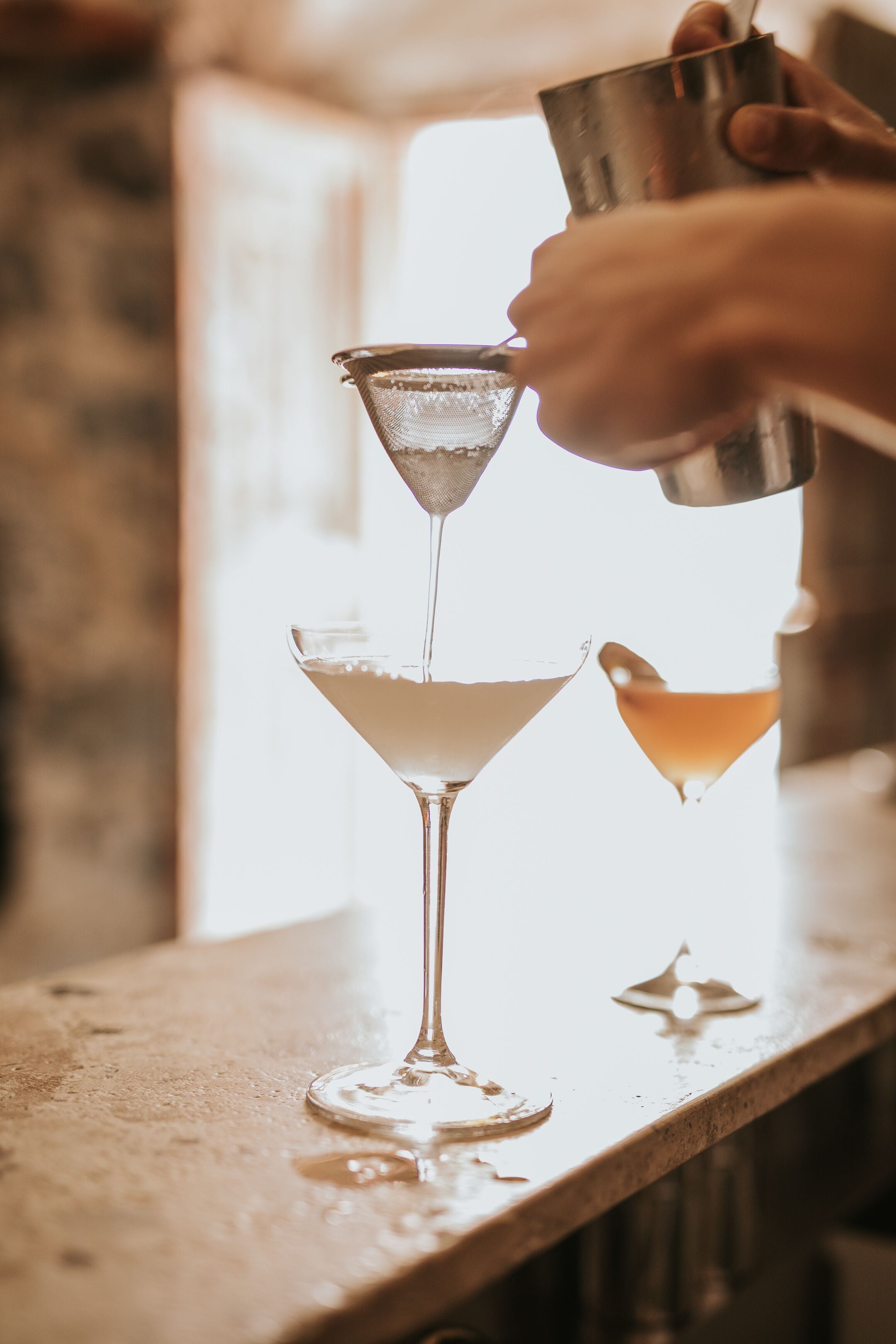 A bartender pouring a drink into a martini glass.