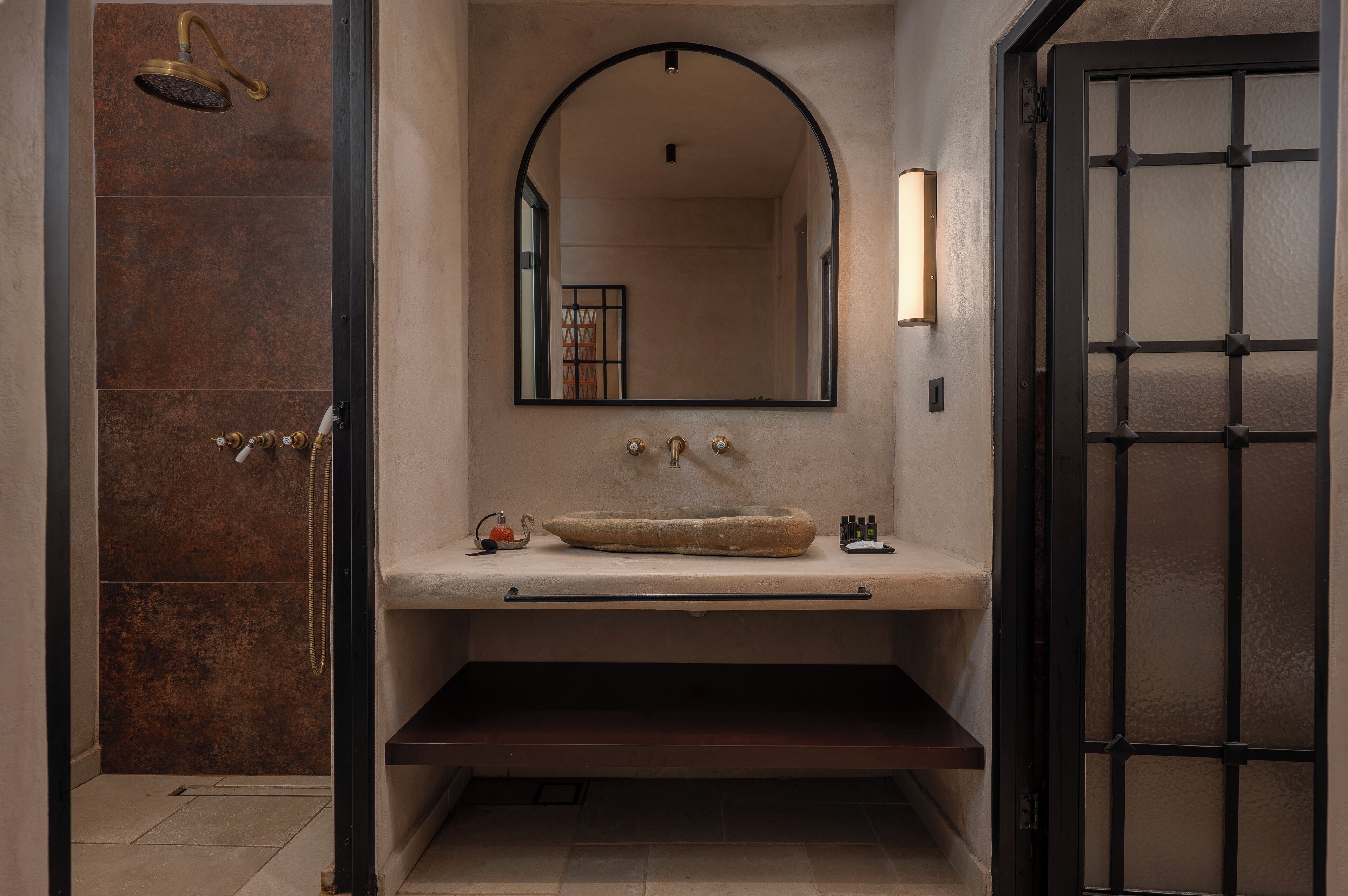 Un baño con ducha, lavabo de piedra y espejo sobre el lavabo.