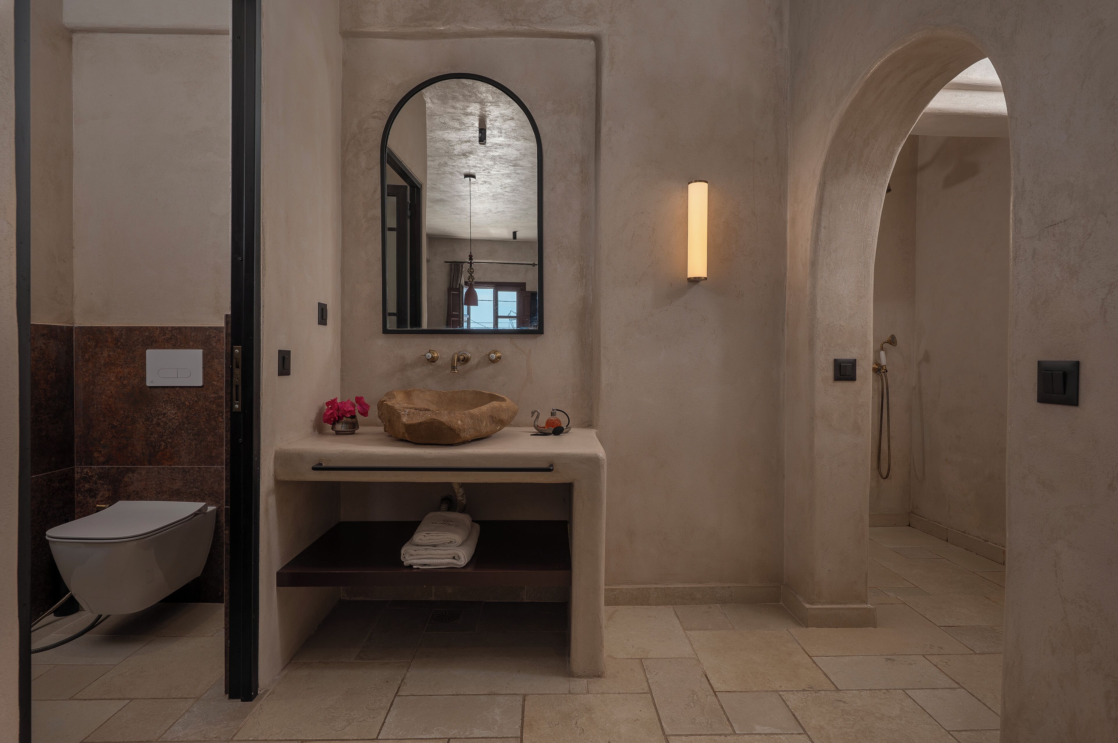 Ein modernes Badezimmer mit einer freistehenden Badewanne, einem großen Spiegel und einer Sitzbank mit Handtüchern.