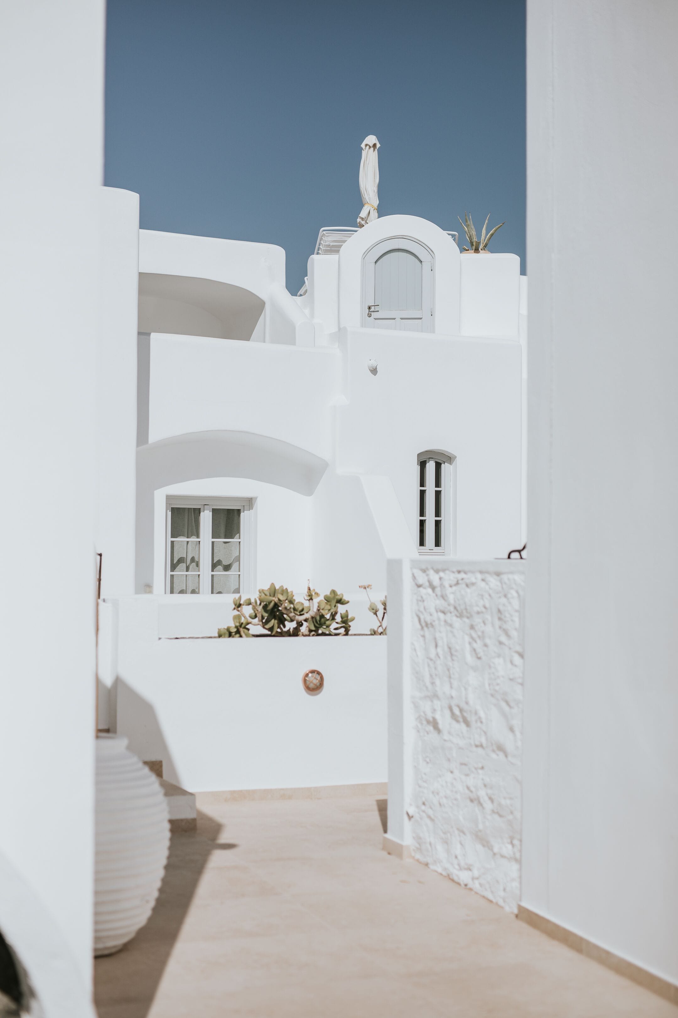 A narrow, white-walled corridor with a marble wall and a small window.