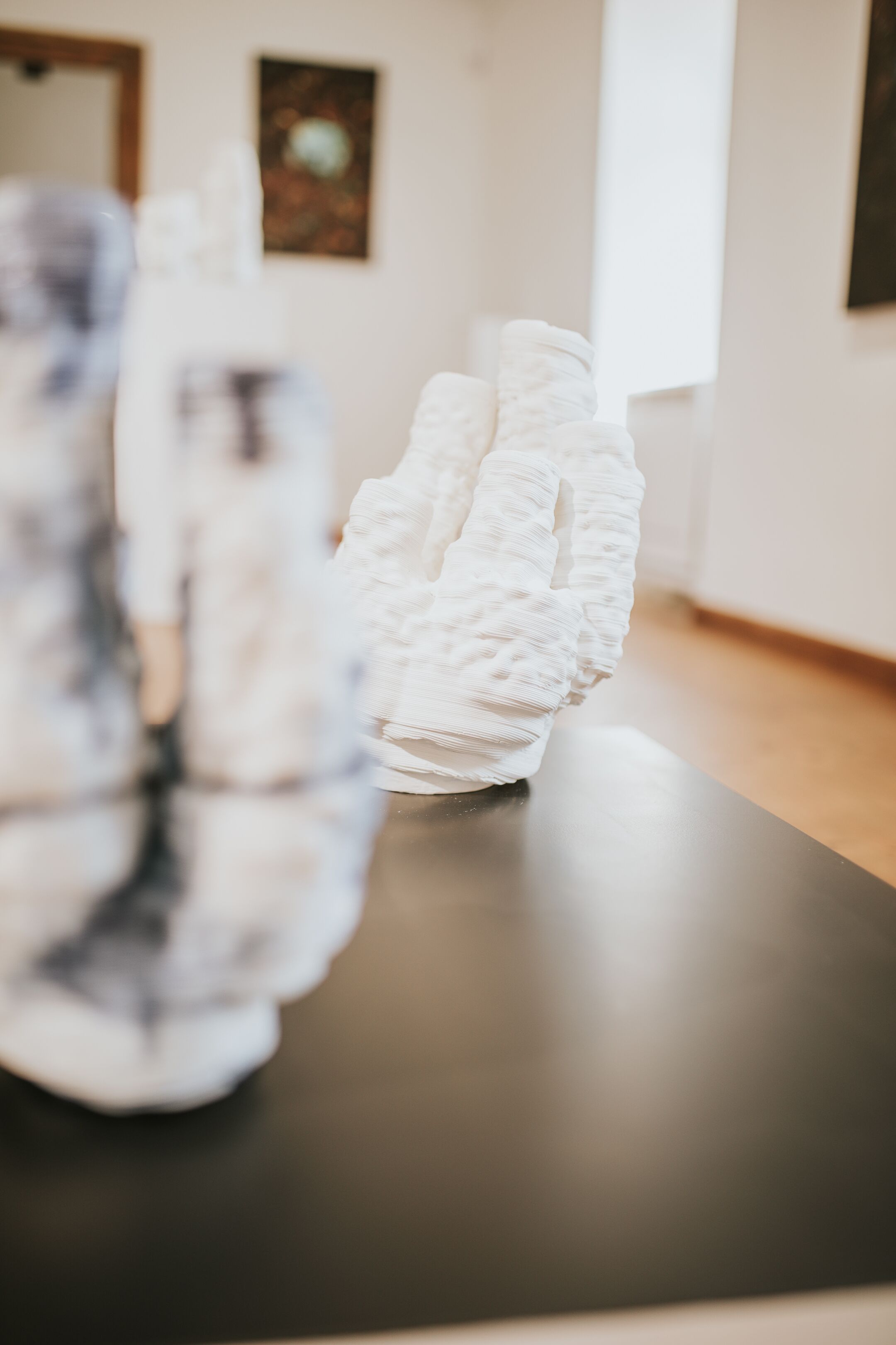 A 3D-printed sculpture on a table in a room with a wooden floor and a framed picture on the wall.