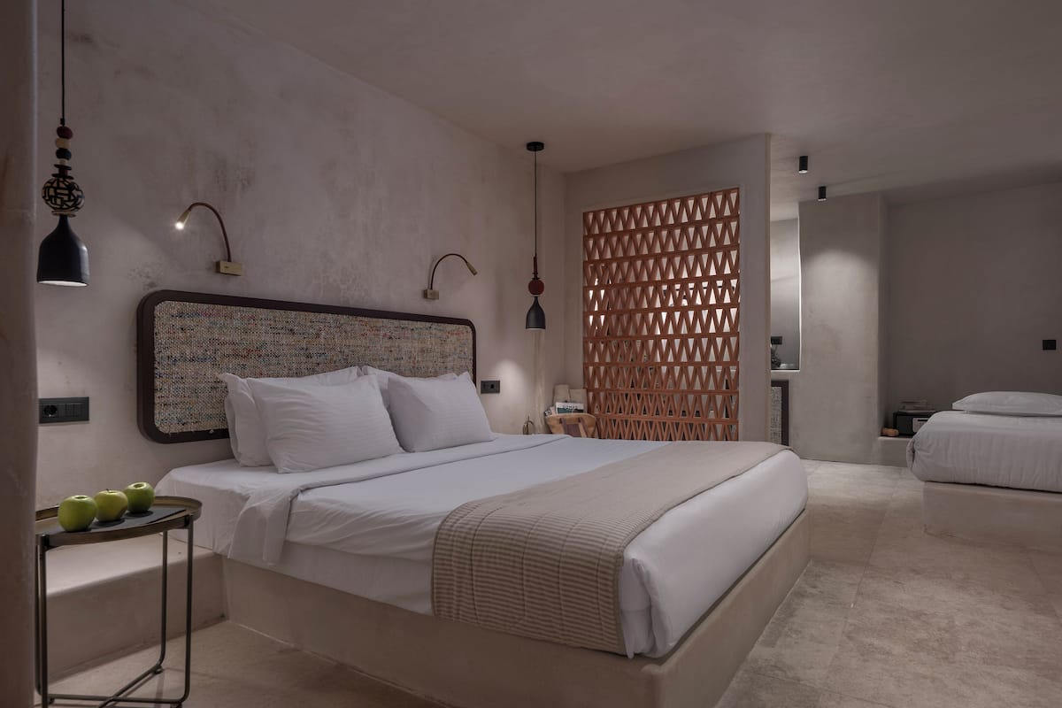 Une chambre moderne avec un grand lit, des tables de chevet, une tête de lit décorative et un mur de séparation.