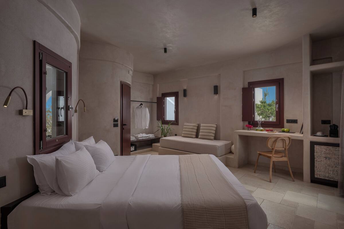 Une chambre avec un grand lit, un bureau, une chaise et une petite kitchenette.