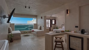 Ein modernes Hotelzimmer mit Balkon, Sitzecke, Küchenzeile und Bett.