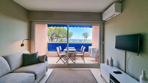 A room with a sofa, a TV, a small table, and a balcony with a table and chairs. - Apartment 4 guests with access to the beach/Fréjus (Fréjus)