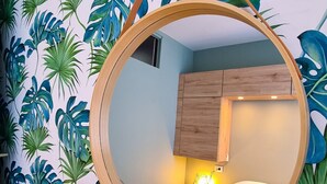 A bedroom with a round mirror, wooden headboard, and a bed with a white comforter. - Apartment 4 guests with access to the beach/Fréjus (Fréjus)