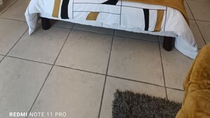 Une chambre à coucher comprenant un lit, des tables de chevet, une œuvre d’art murale et des éléments décoratifs fixés au mur.