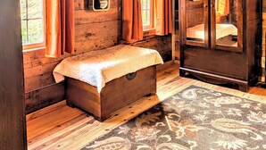 A rustic cabin interior with wooden walls, a bench, a cabinet, and a patterned rug. - Cozy 1 - Bedroom Cabin in Cooper's Creek Area (Suches)
