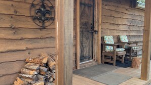 A wooden cabin with a porch, a door, and a stack of firewood. - Cozy 1 - Bedroom Cabin in Cooper's Creek Area (Suches)