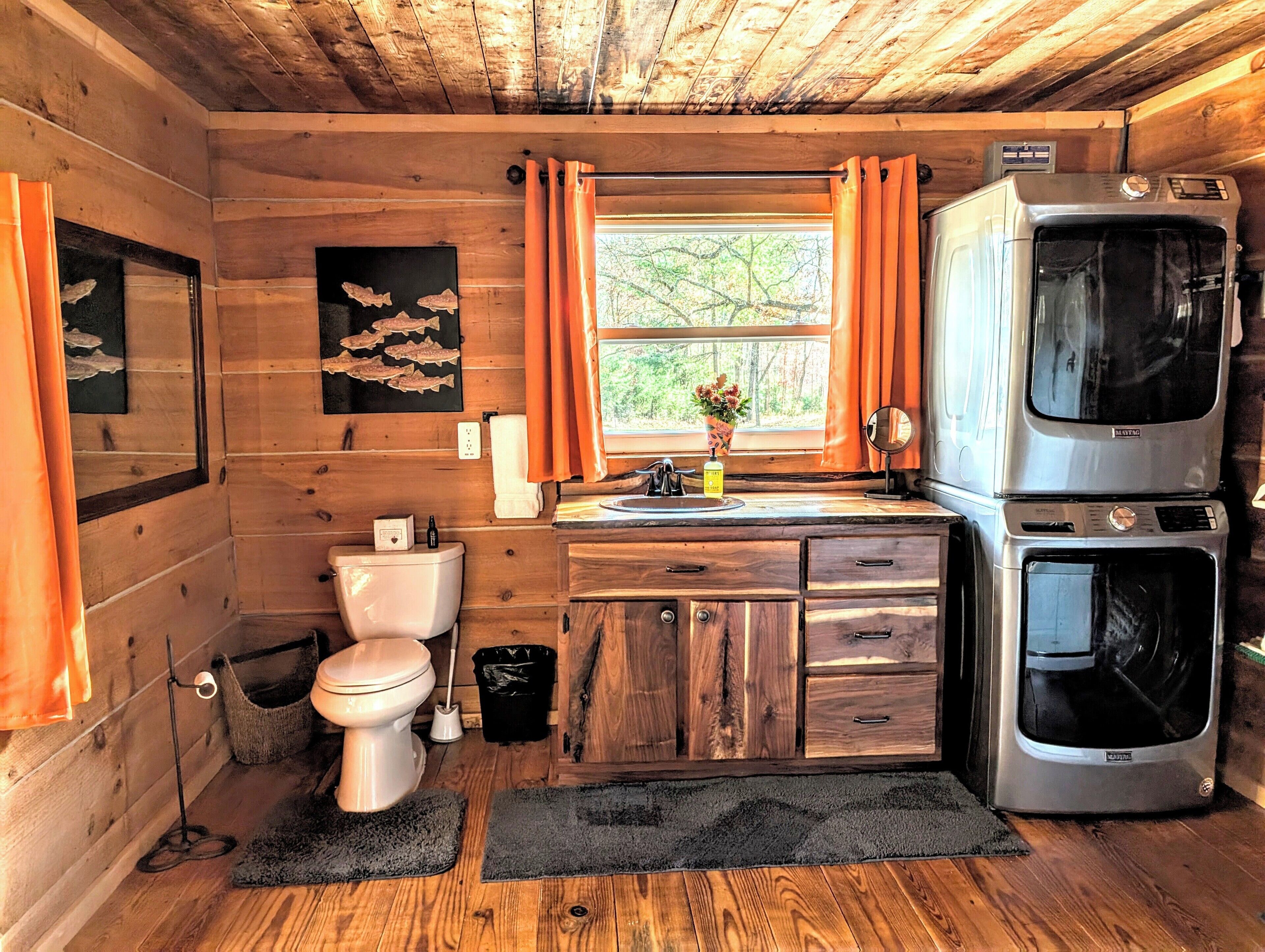 A compact kitchen with wooden cabinets, a sink, a toilet, and a refrigerator.