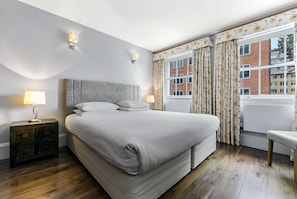 A bedroom with a large bed, two bedside lamps, a nightstand, and a window with curtains. - 3 bedroom family apartment with private terrace (London)