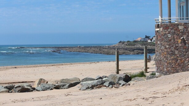 Une plage avec une tour de guet en pierre, un rivage rocheux et une vue dégagée sur l’océan.