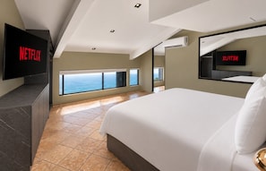 A modern hotel room with a large bed, a TV mounted on the wall, and a view of the ocean. - Penthouse deluxe, 360º views and glass pool (Ciudad de Panamá)
