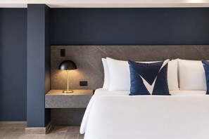 Een hotelkamer met een bed, nachtkastje, lamp en hoofdeinde.