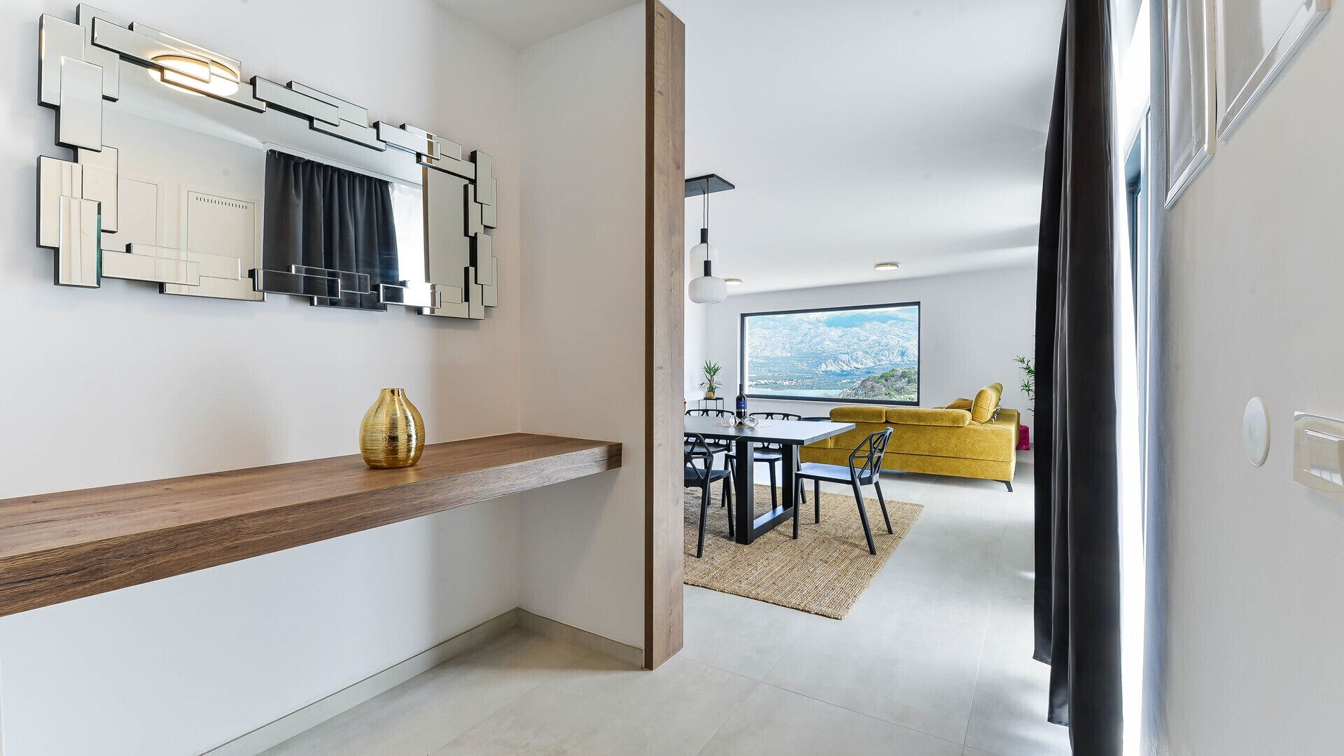 Une cuisine moderne avec un plan de travail en bois, un grand miroir et un canapé jaune dans l’espace repas.