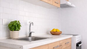 A kitchen with wooden cabinets, a white countertop, a sink, a stove, and a potted plant. - Grand Seaview Retreat - walk to the beach (Thessaloniki)