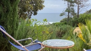 A garden with a view of the sea, featuring a table and chairs. - Pieds dans l'eau Secret Creek (Conca)