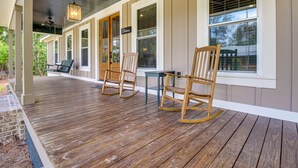 A covered porch with wooden flooring, rocking chairs, and a table. - Spacious Midway Cottage w/ Porches, Near Hunting! (Midway)