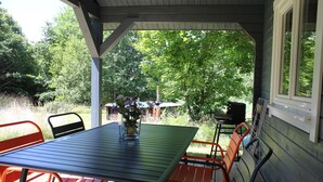 An outdoor patio with a table and chairs, surrounded by greenery.