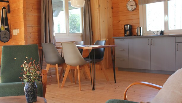 A cozy cabin interior with a dining area, a kitchen, and a living space.