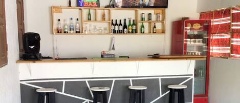 Zona de bar con mostrador, taburetes y una pantalla de televisión que muestra un programa.