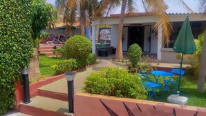 A courtyard with a seating area, palm trees, and a building with a mural.