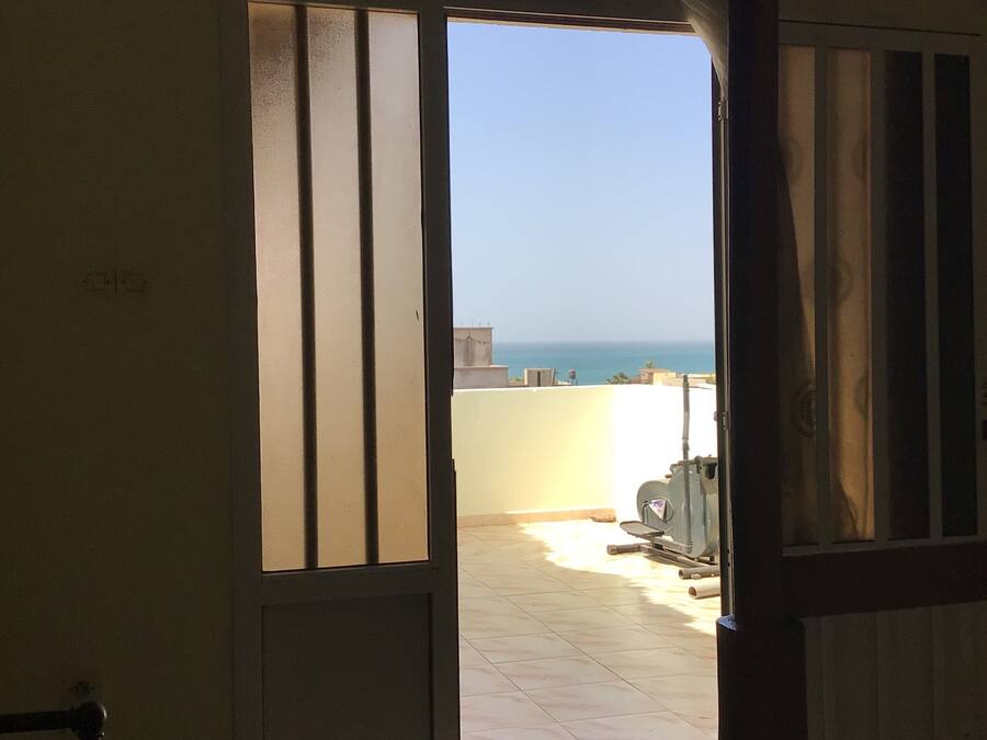 A room with a view of the sea through a sliding door.