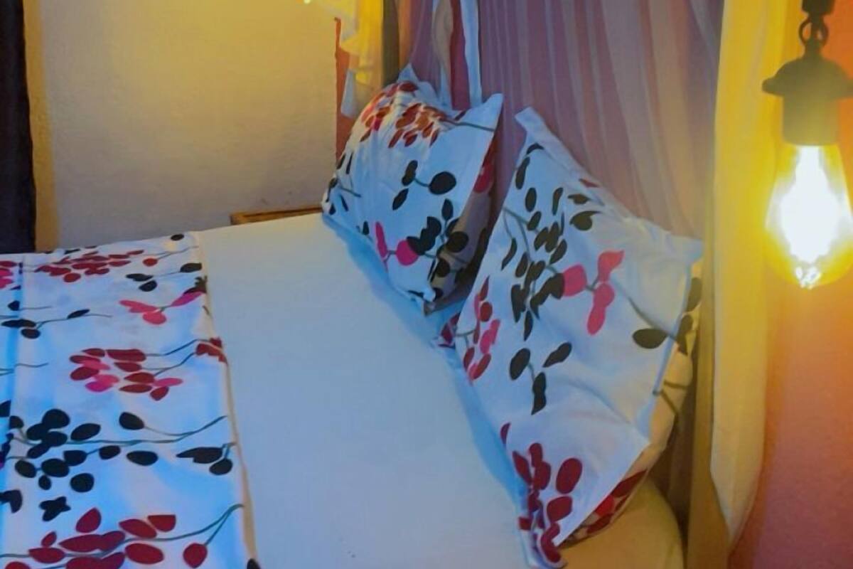 A bed with a canopy, a round mirror, and a hanging light fixture.
