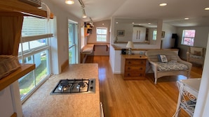 A spacious kitchen with a gas stove, wooden cabinets, and a large window.