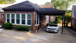 A residential house with a covered garage and a white car parked inside.