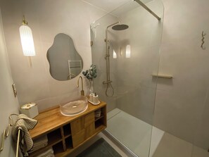 A modern bathroom with a wooden vanity, a glass shower enclosure, and a wall-mounted mirror.