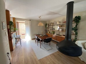 Un salon comprenant un coin repas, une grande cheminĂ©e noire et une bibliothĂšque remplie de livres et dâobjets dĂ©coratifs.