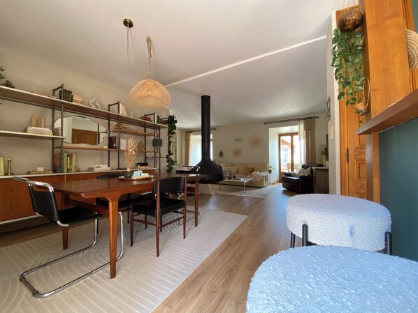 Un grand espace de vie comprenant une table à manger, des chaises, un canapé, une cheminée et une bibliothÚque.
