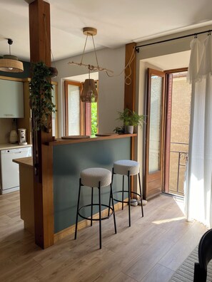 Une cuisine avec des meubles en bois, une machine à café et une plante suspendue.