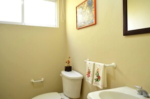 A bathroom with a toilet, sink, and a window.