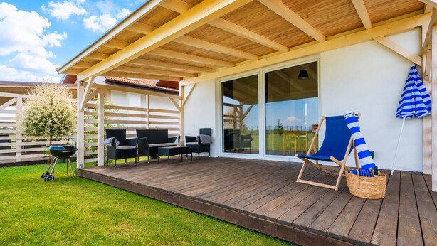 Eine Terrasse im Freien mit einer Pergola, einem Grill und Sitzgelegenheiten.