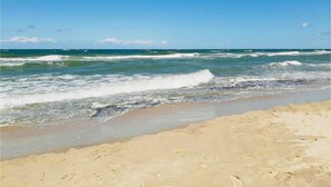 Ein Strand mit brechenden Wellen unter blauem Himmel.