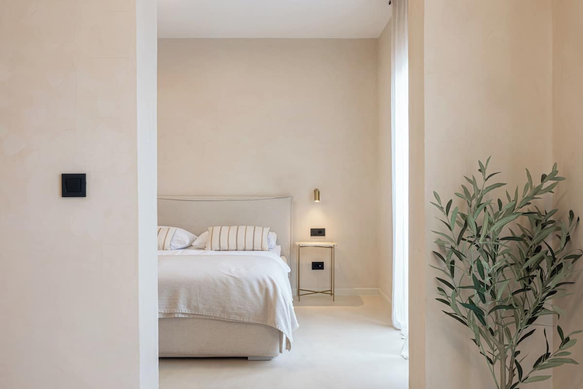 A bedroom with a bed, bedside table, and a potted plant.