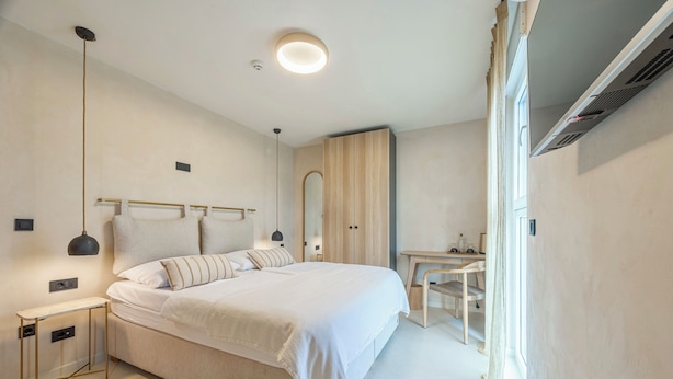 A modern bedroom with a large bed, bedside tables, a desk, and a wardrobe.